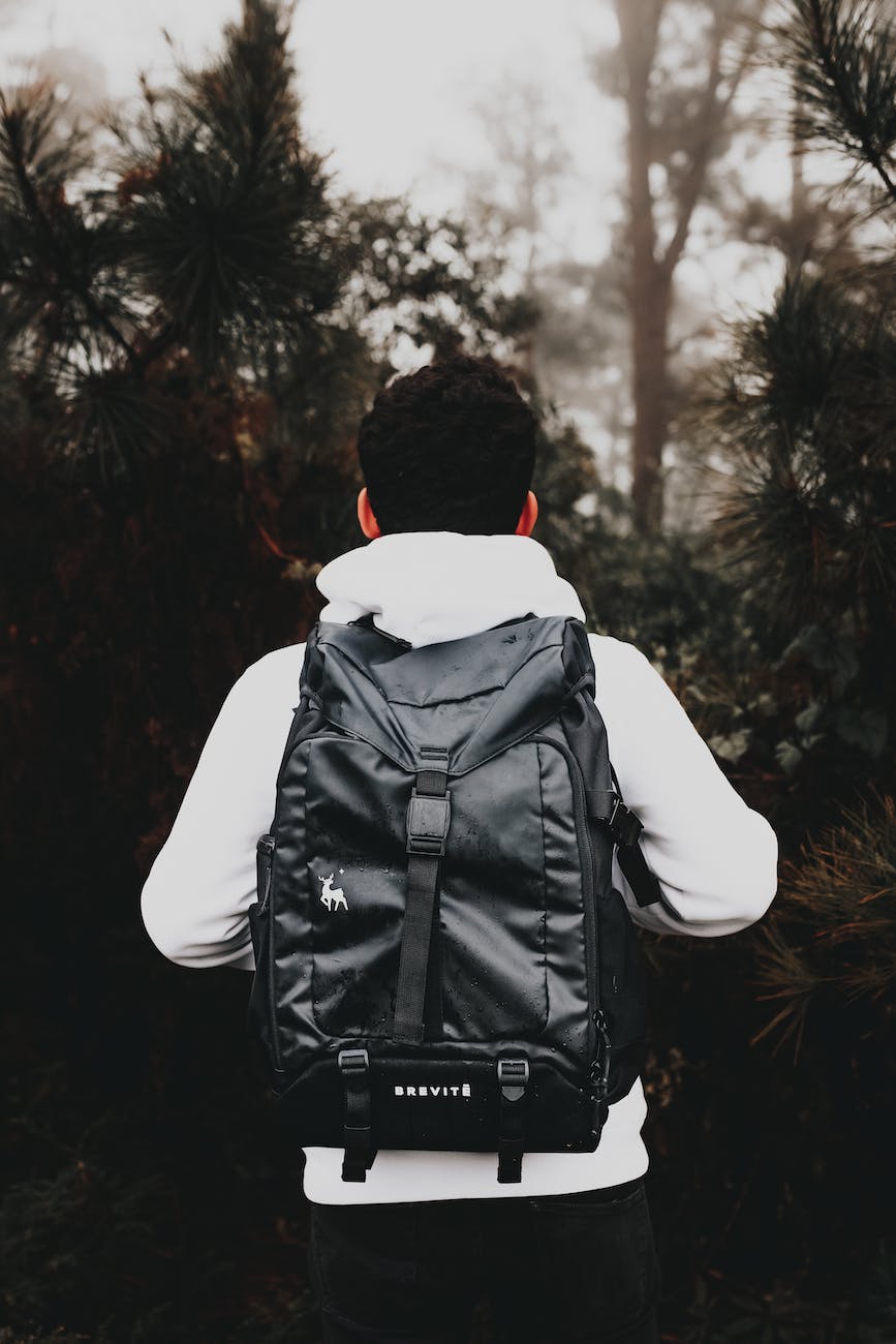 faceless male tourist with stylish rucksack in foggy forest